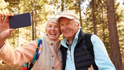 Glückliche Senioren machen ein Selfie beim Waldspaziergang.
