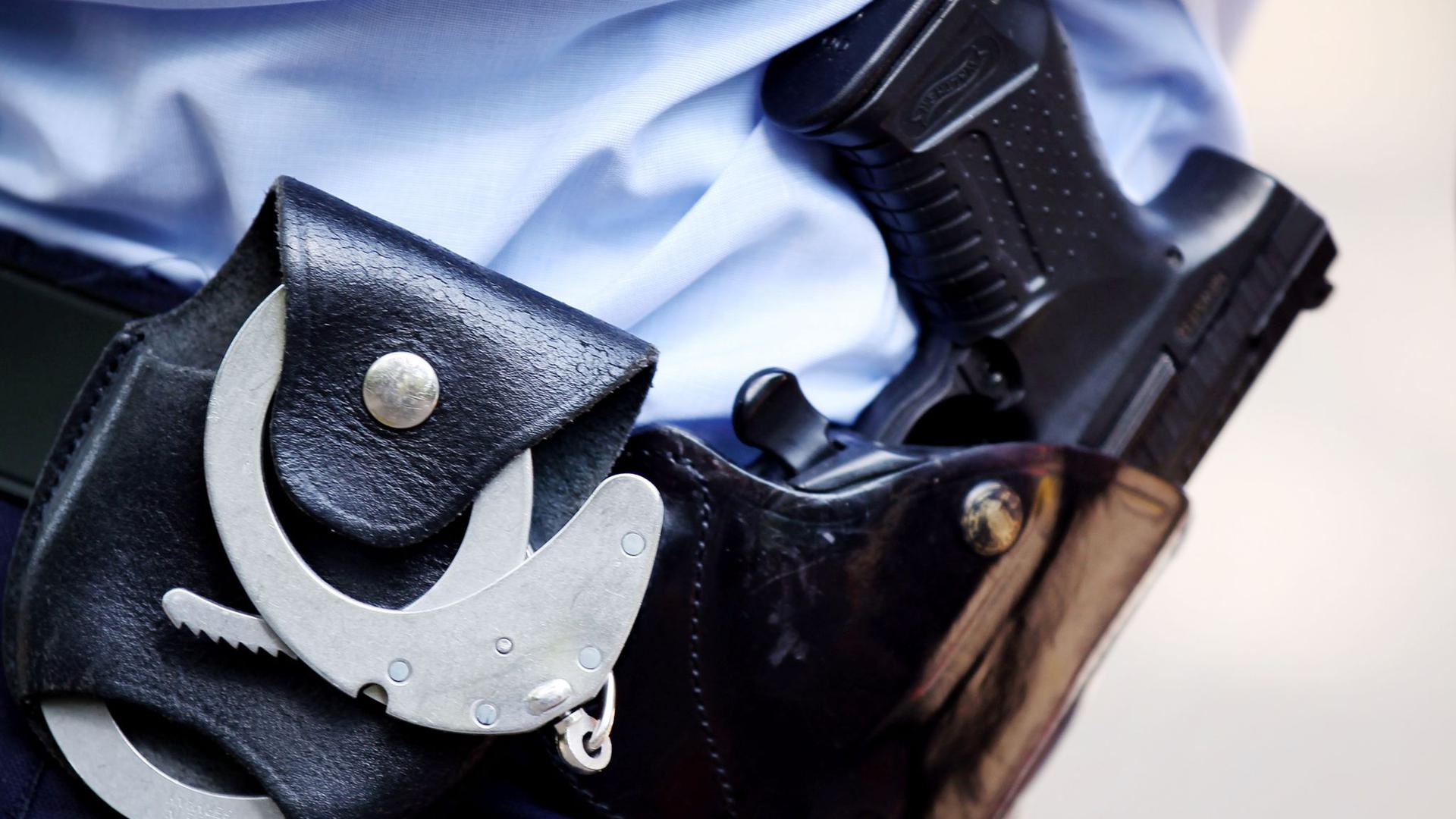 Handschellen und Pistole am Gürtel eines Polizisten.