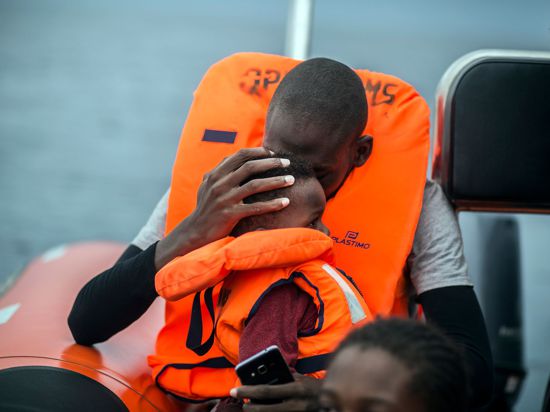 Ein Mann hält seinen Sohn im Arm, nachdem er gemeinsam mit anderen Flüchtlingen gerettet wurde.