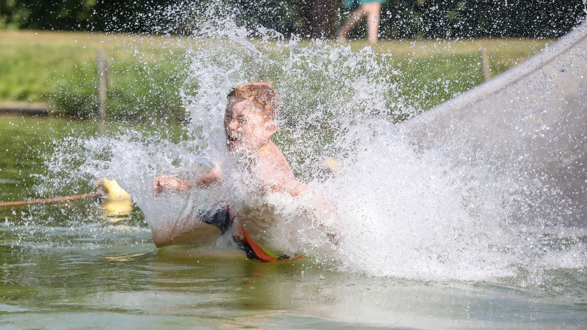 So lässt sich die Hitze aushalten: Ein Junge rutscht eine Wasserrutsche hinunter.