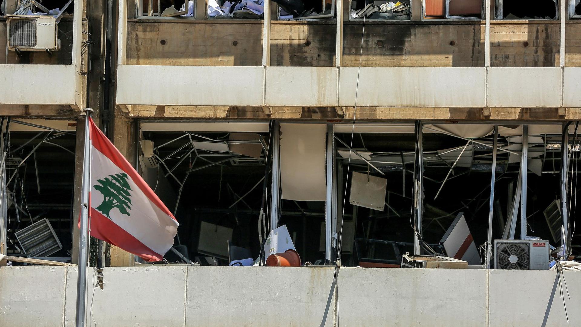 Die libanesische Flagge vor der Fassade
eines zerstörten Bürogebäudes in Beirut.