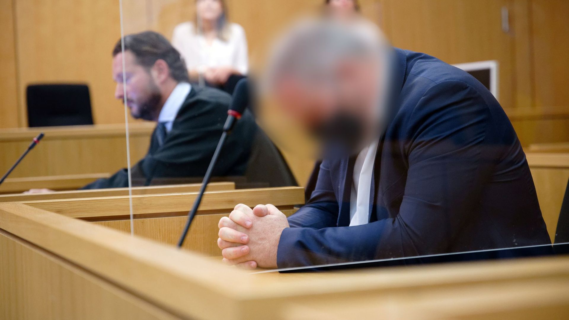 Der Angeklagte sitzt vor Beginn seines Prozesses in einem Saal des Aachener Landgerichts neben seinem Rechtsanwalt.