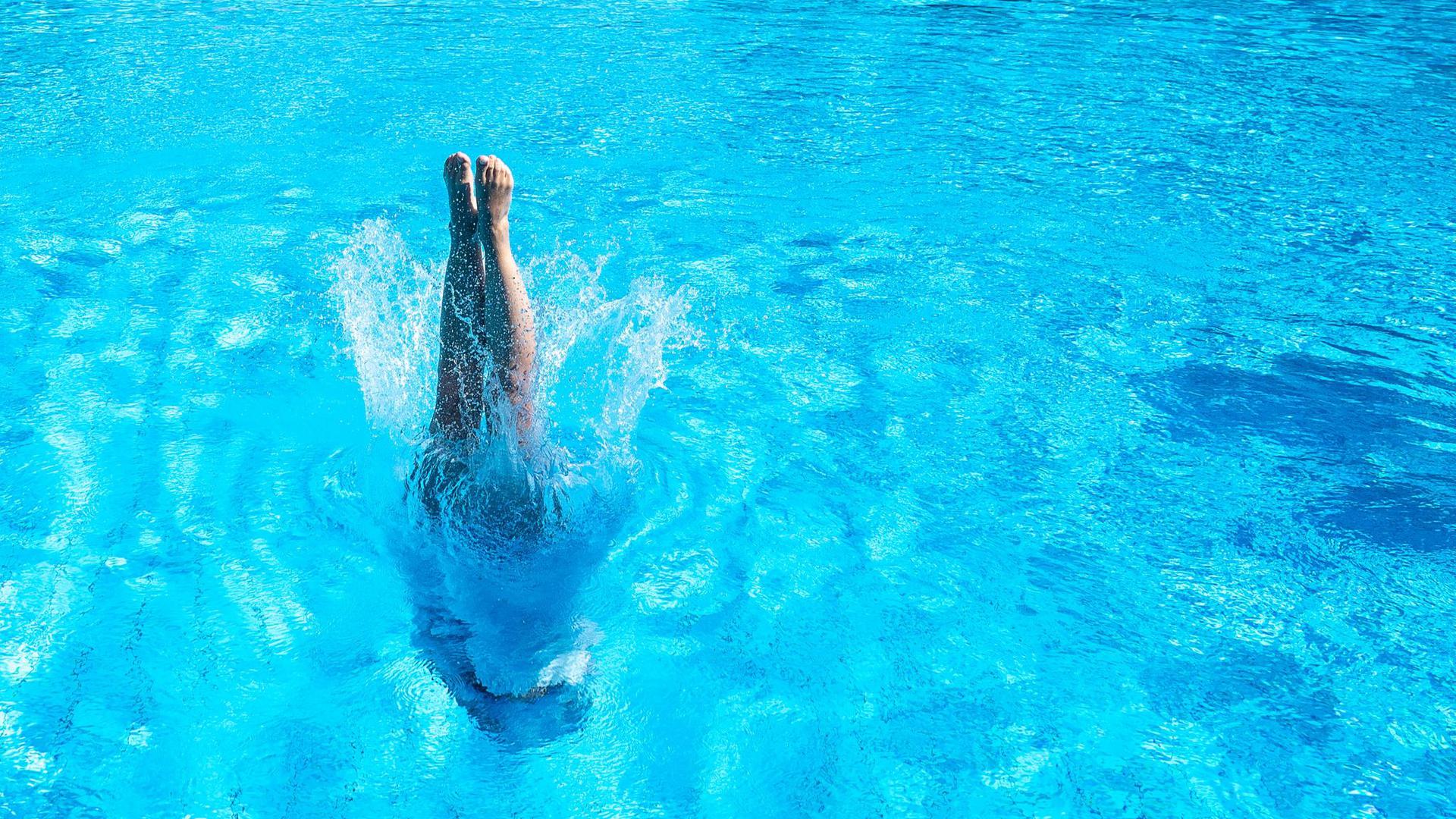 Eine Frau taucht im Stuttgarter Inselbad ins Becken ein.