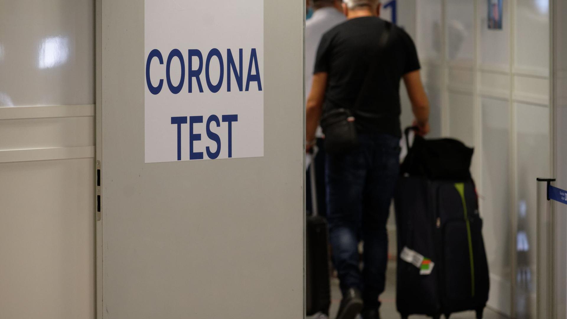 Reiserückkehrer gehen im Flughafen Düsseldorf zum Corona-Testzentrum.