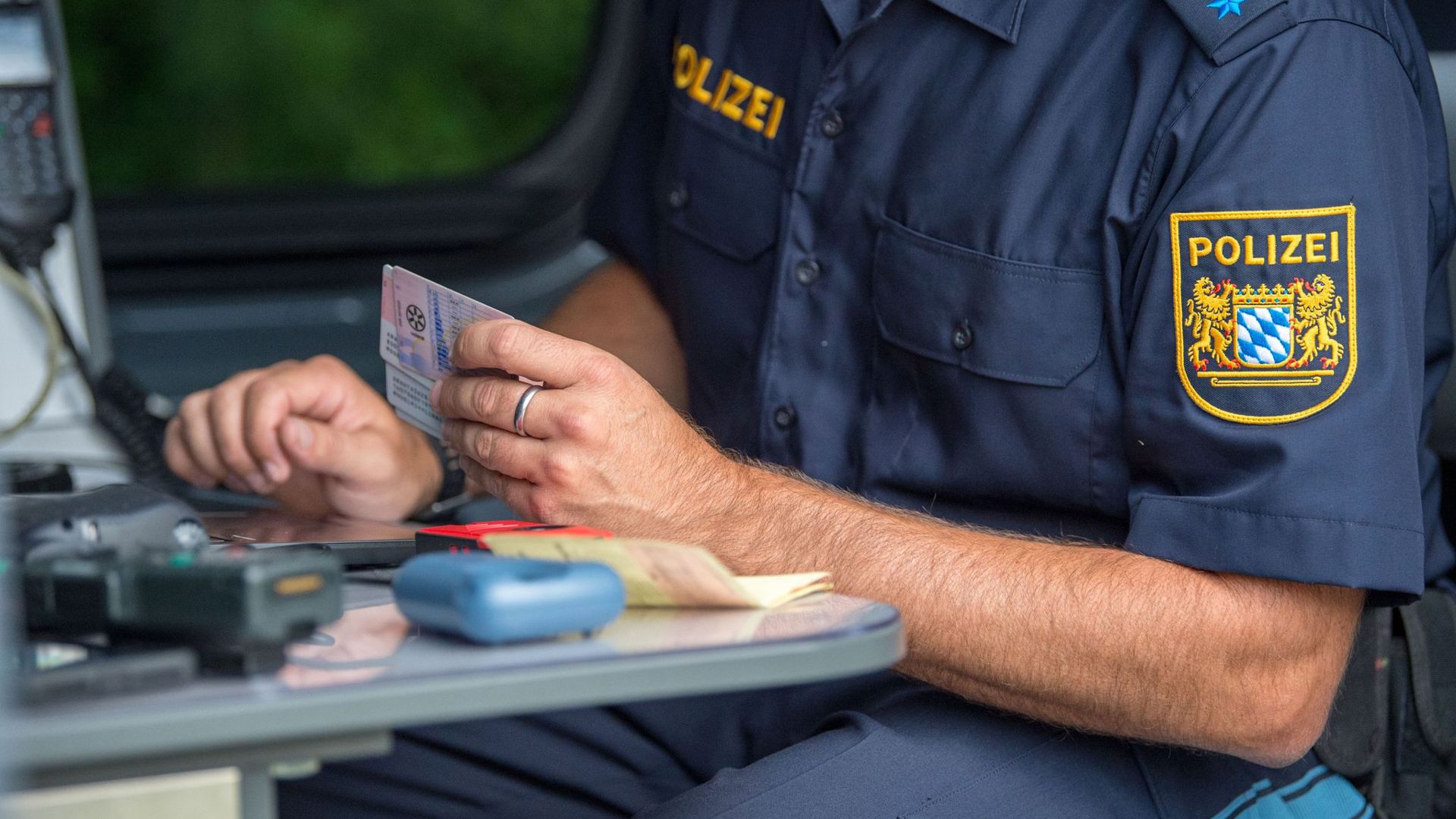 Ein Beamter der bayerischen Grenzpolizei kontrolliert am Grenzübergang Kirchdorf Dokumente von Autofahrern.