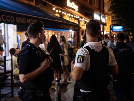 Vor einem Berliner Lokal kontrollieren Polizisten eine Party.
