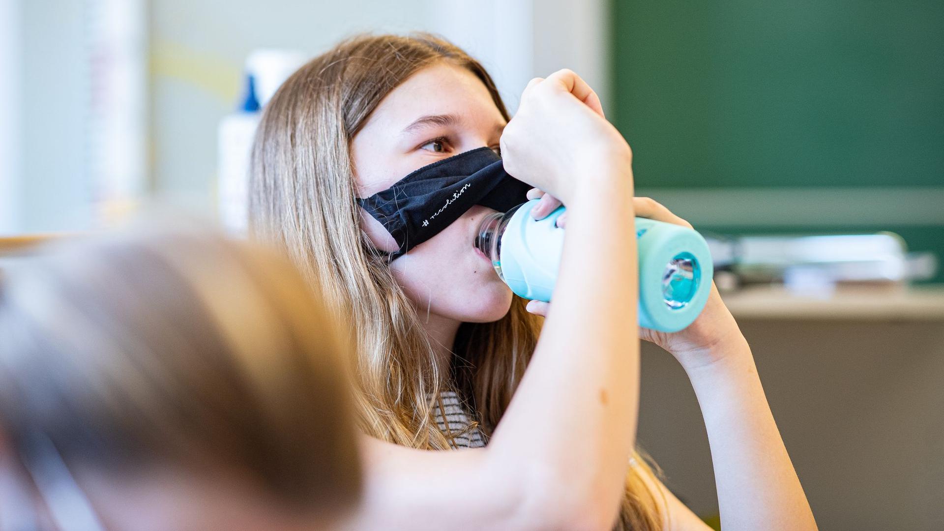 Eine Schülerin der Klasse 8a der Gesamtschule in Münster hebt ihre Mund- und Nasenmaske an, um etwas zu trinken.