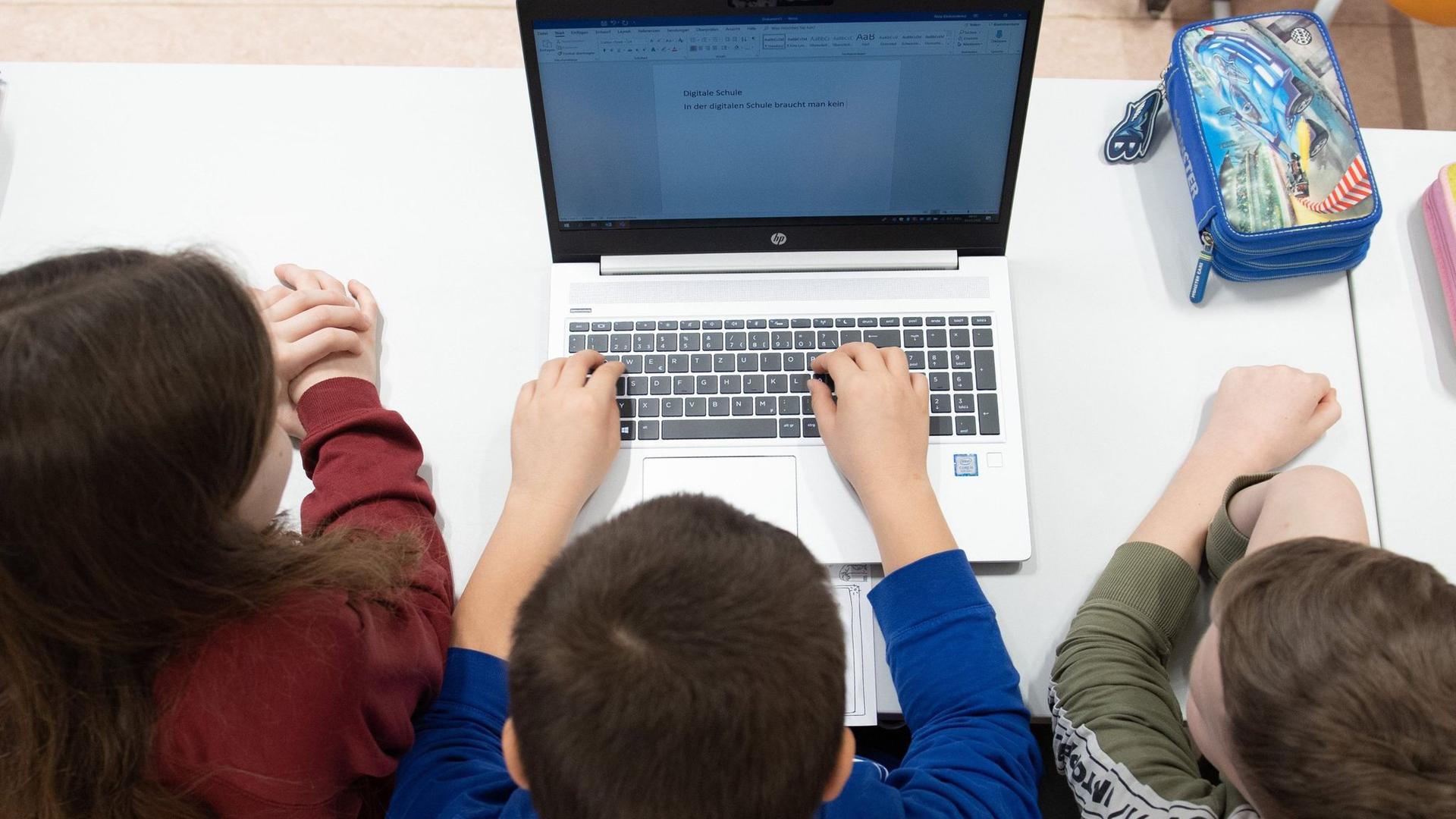 Schüler einer 3. Klasse sitzen während eines Presserundgangs in einem Klassenzimmer der Grundschule Georgius Agricola vor einem Laptop.
