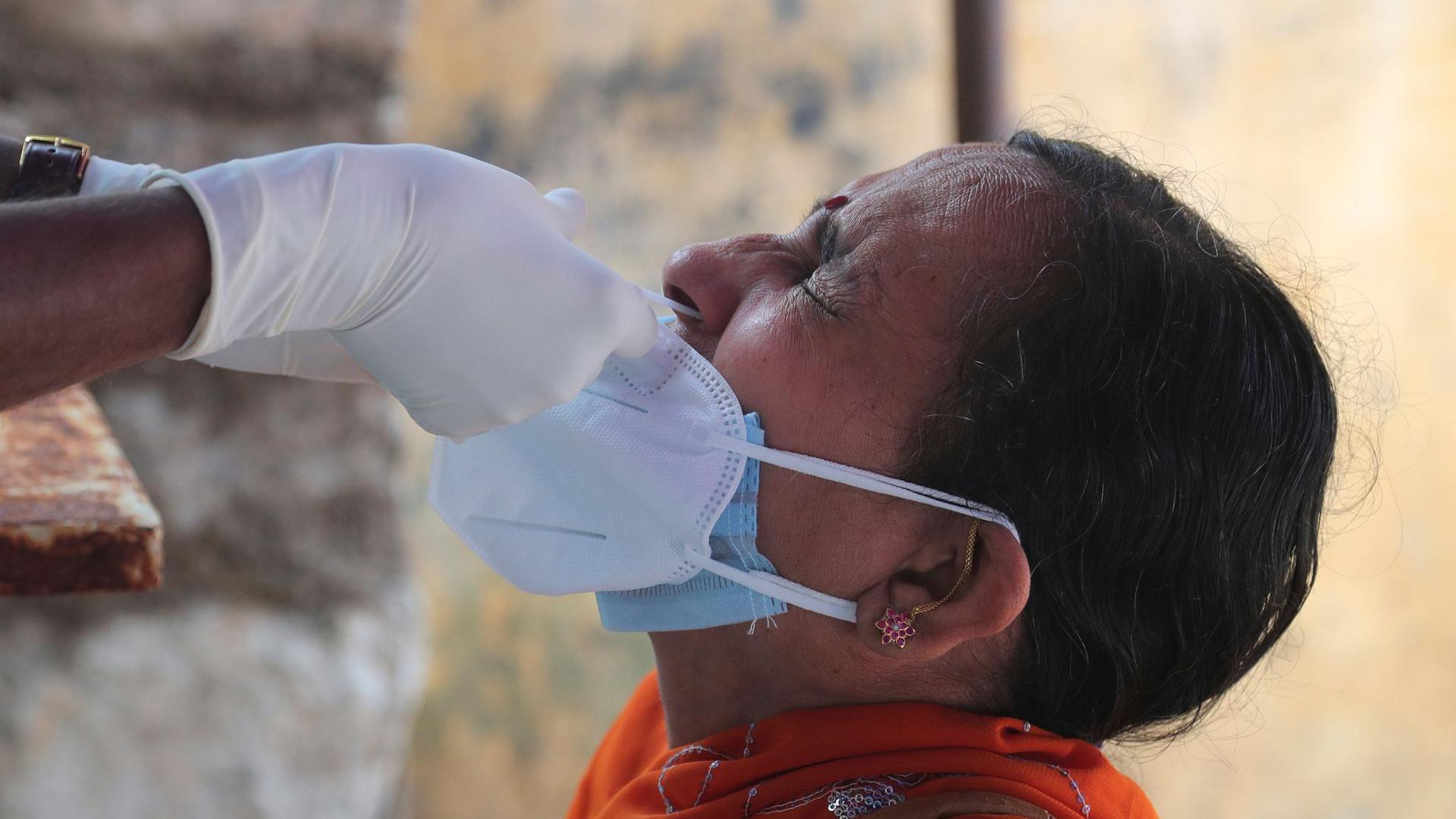 Ein medizinischer Mitarbeiterin der indischen Stadt Hyderabad entnimmt einer Frau einen Nasenabstrich für einen Corona-Test.