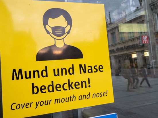 Auf dem Münchener Marienplatz fordert ein Schild zum Tragen eine Mund-Nasen-Bedeckung auf.