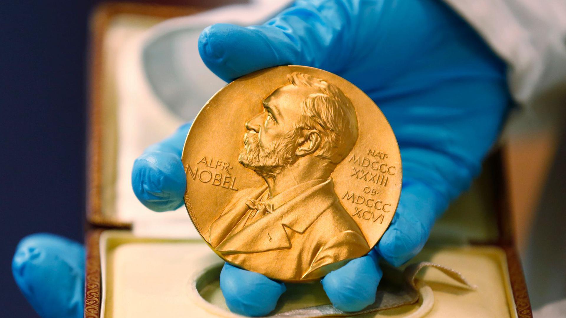 Ein Mitarbeiter der Nationalbibliothek zeigt eine goldene Nobelpreismedaille.