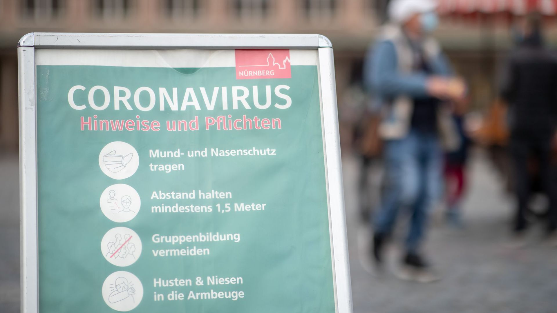 Ein Schild informiert Passanten auf dem Nürnberger Hauptmarkt über die Maskenpflicht und weitere Regeln.