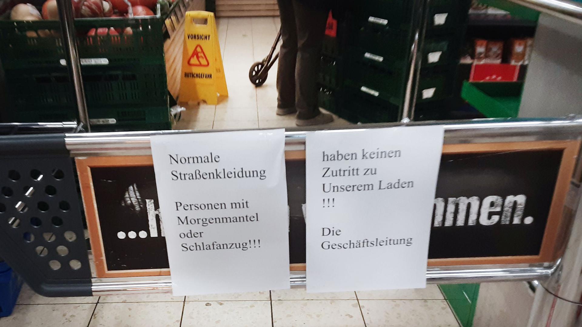 Hinweiszettel machen die Kundschaft in dem Duisburger Supermarkt auf die nun geltende Kleiderordnung aufmerksam.