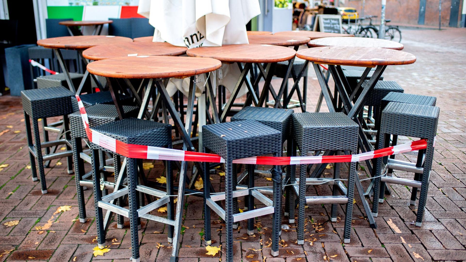 Tische und Stühle stehen abgesperrt vor einer Pizzeria.