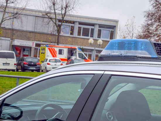 Einsatzfahrzeuge von Polizei und Rettungsdiensten stehen vor einer Schule in Östringen, an der ein 13-Jähriger einen Mitschüler attackierte.