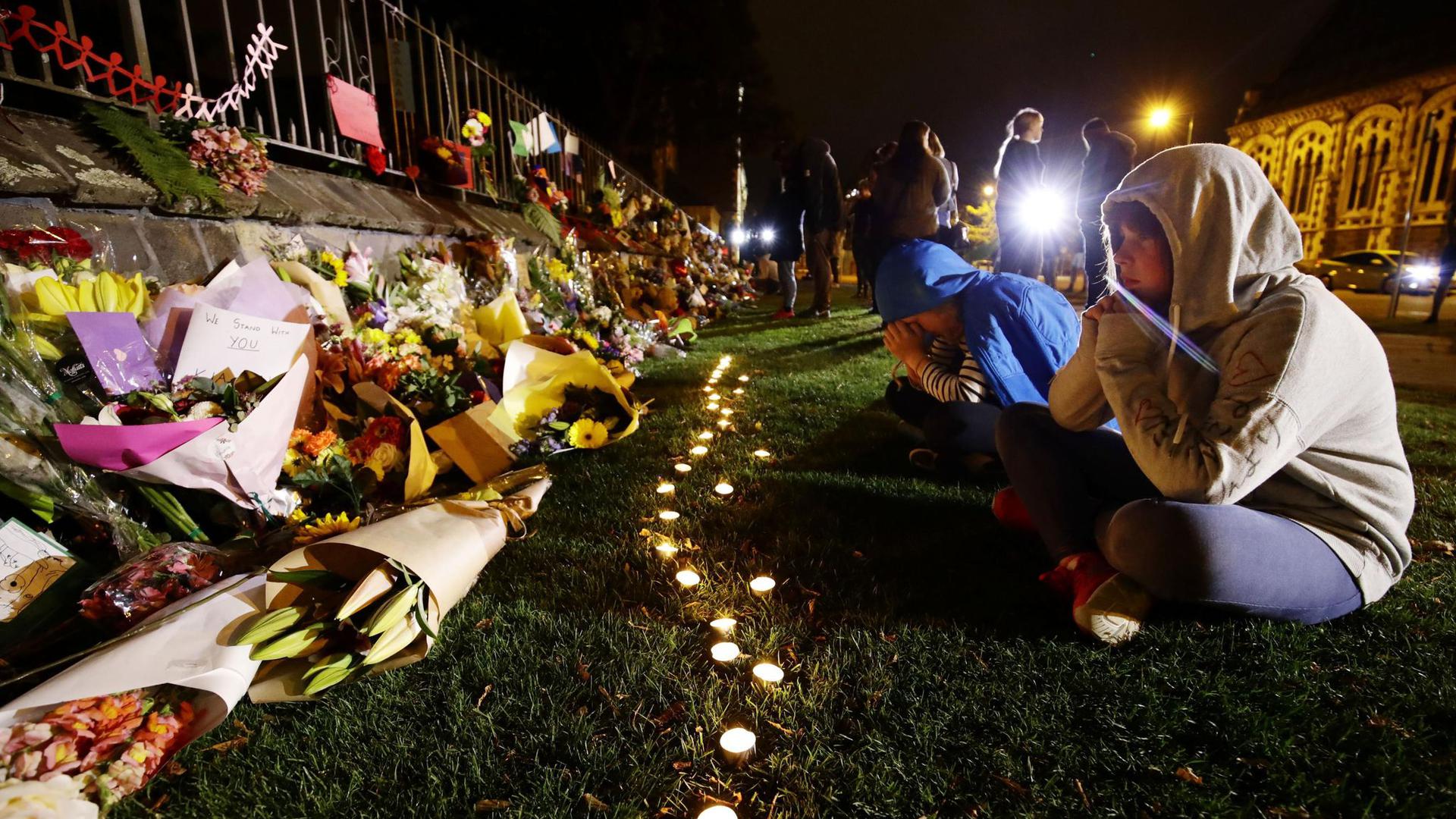 Menschen trauern vor Kerzen und Blumen, die in Gedenken an die Opfer der Anschläge auf zwei Moscheen in Christchurch, Neuseeland niedergelegt wurden.