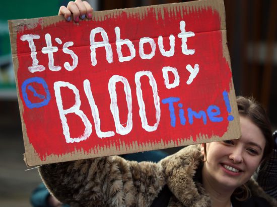 Eine Frau in Edinburgh hält bei einer Kundgebung ein Schild mit der Aufschrift „It's about bloody time!“ (dt. Es ist verdammt noch mal an der Zeit) hoch.
