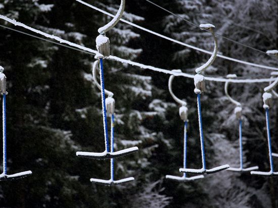 Bügel eines Schleppliftes hängen in schneebedeckter Landschaft. Wegen der Maßnahmen um das Coronavirus müssen Skilifte geschlossen bleiben.