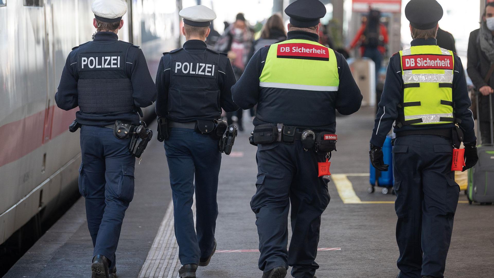 Polizeibeamte und Mitarbeiter der DB-Sicherheit kontrollieren am Stuttgarter Hauptbahnhof die Maskenpflicht.