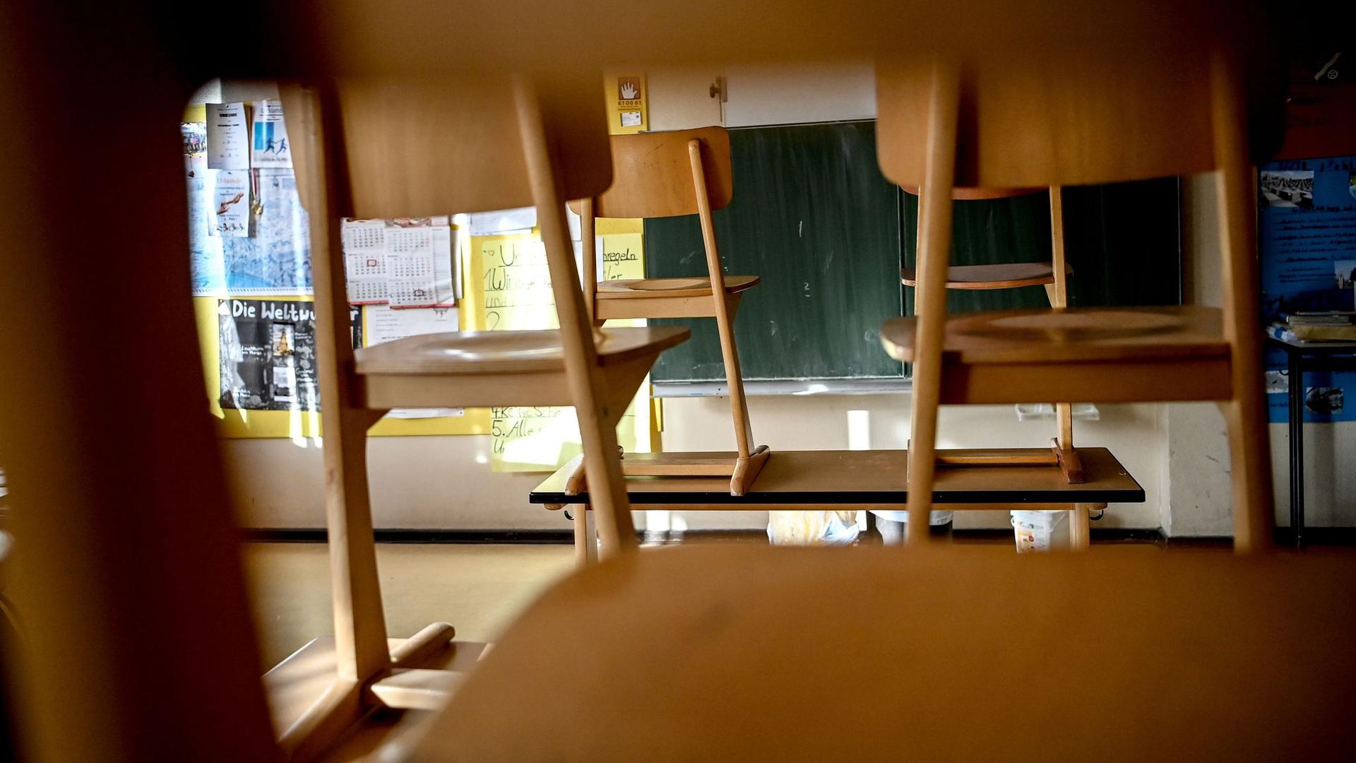 Stühle sind in einem Klassenzimmer einer Grundschule hochgestellt. Der Schulbetrieb steht während der Corona-Krise vor großen Herausforderungen.