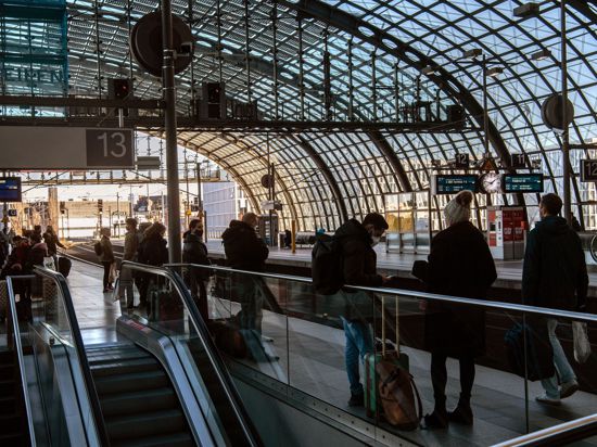 Reisende warten im Hauptbahnhof in Berlin auf einen Zug.