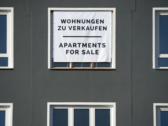 Mit einem großen Plakat werden Wohnungen zum Kauf angeboten. Weniger Maklerkosten entlasten Immobilienkäufer vor allem in Städten, wo Häuser und Wohnungen sehr teuer sind.