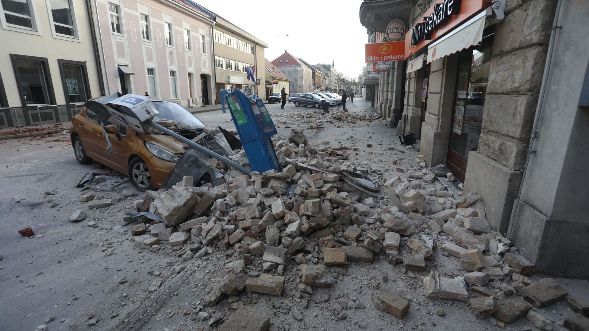 Trümmer eines durch ein Erdbeben eingestürzten Hauses bedecken ein Fahrzeug, das an einer Straße in Sisak steht.