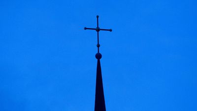 Das Kreuz einer evangelisch-lutherischen Kirche in der Abenddämmerung.