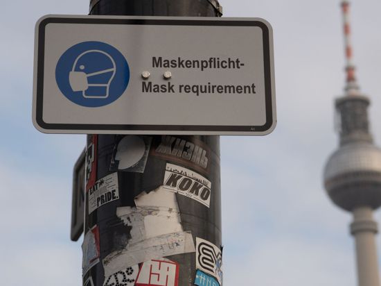 Ein Schild weist in Berlin auf die Maskenpflicht hin.