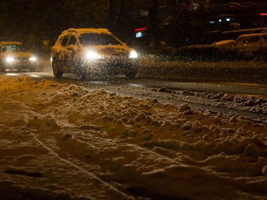 Autos sind in Freiburg im dichten Schneetreiben unterwegs.