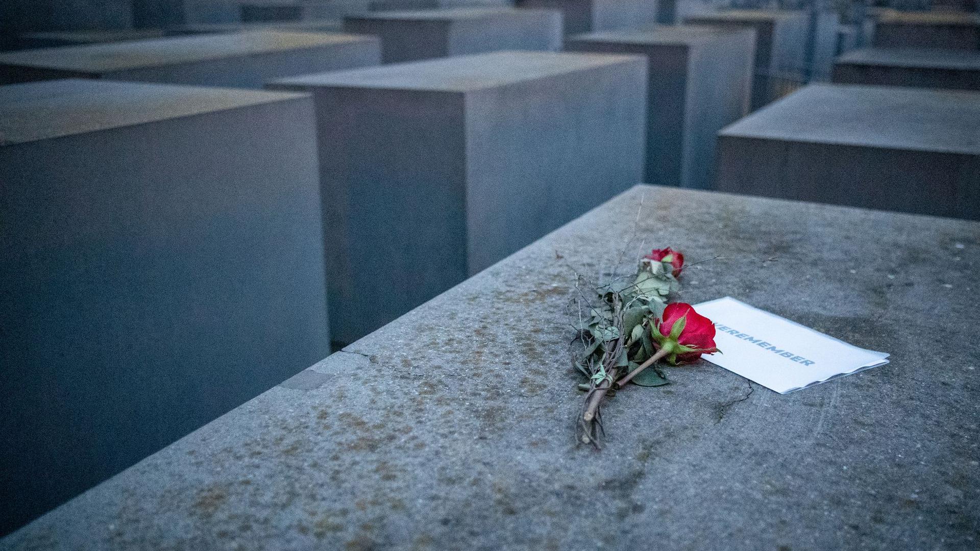 Rosen liegen mit einem Zettel, mit der Aufschrift „#weremeber“ am Holocaust-Mahnmal in Berlin.