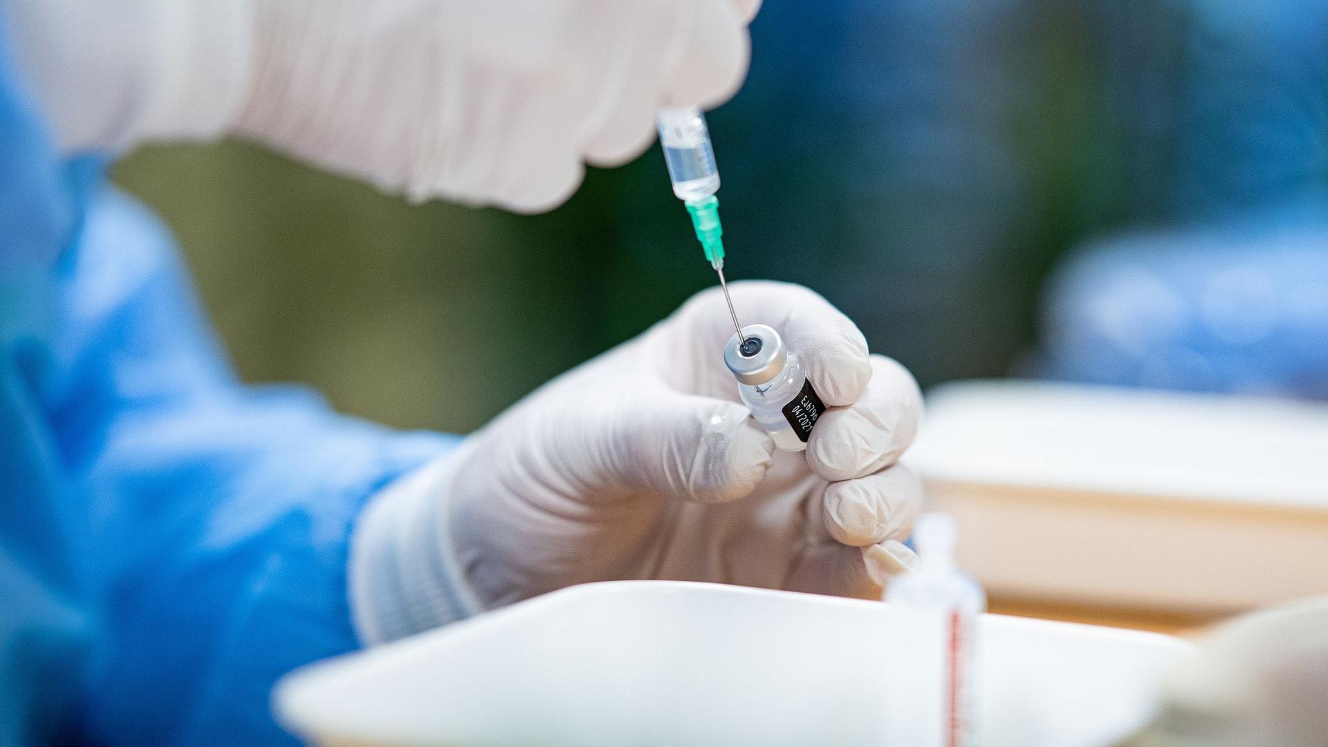 Ein Infektiologe zieht in einem Seniorenheim eine Spritze mit Impfstoff gegen das Coronavirus auf.