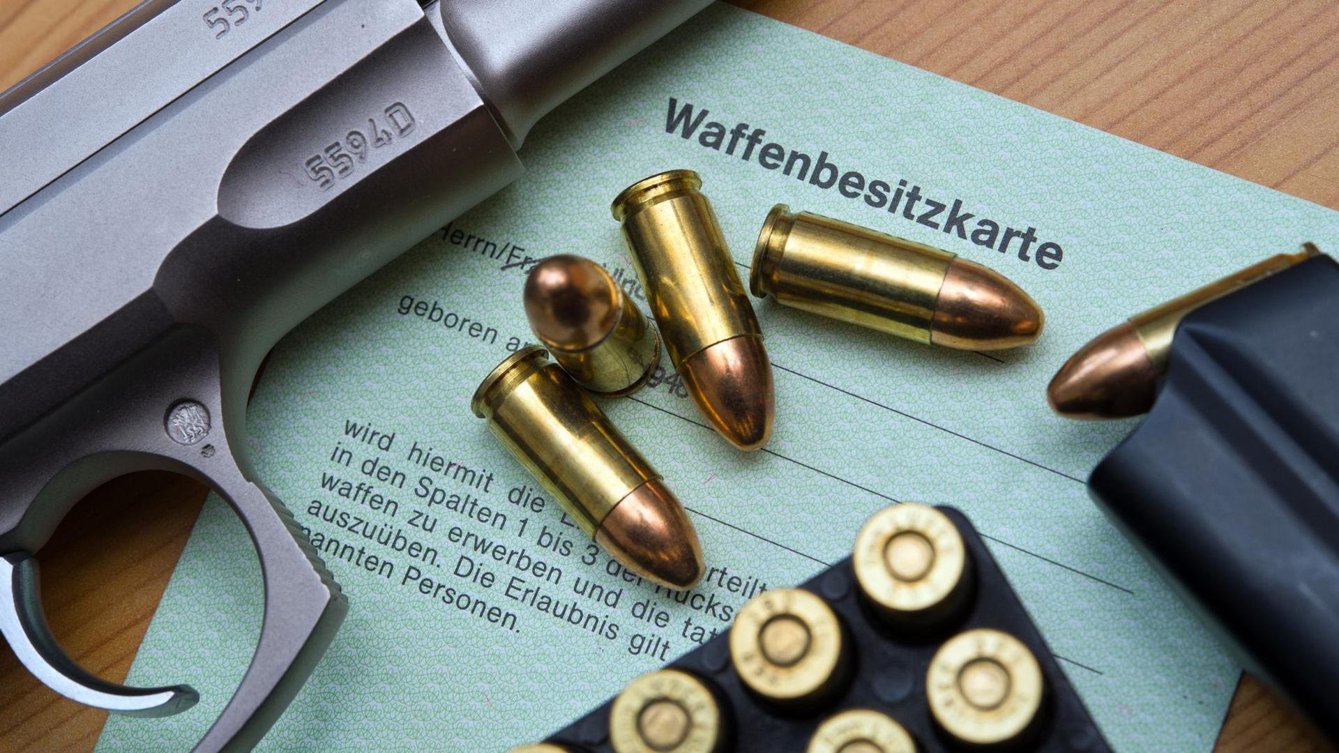 Eine Kaliber 9 mm Pistole, Patronen und ein Magazin liegen auf einer Waffenbesitzkarte.
