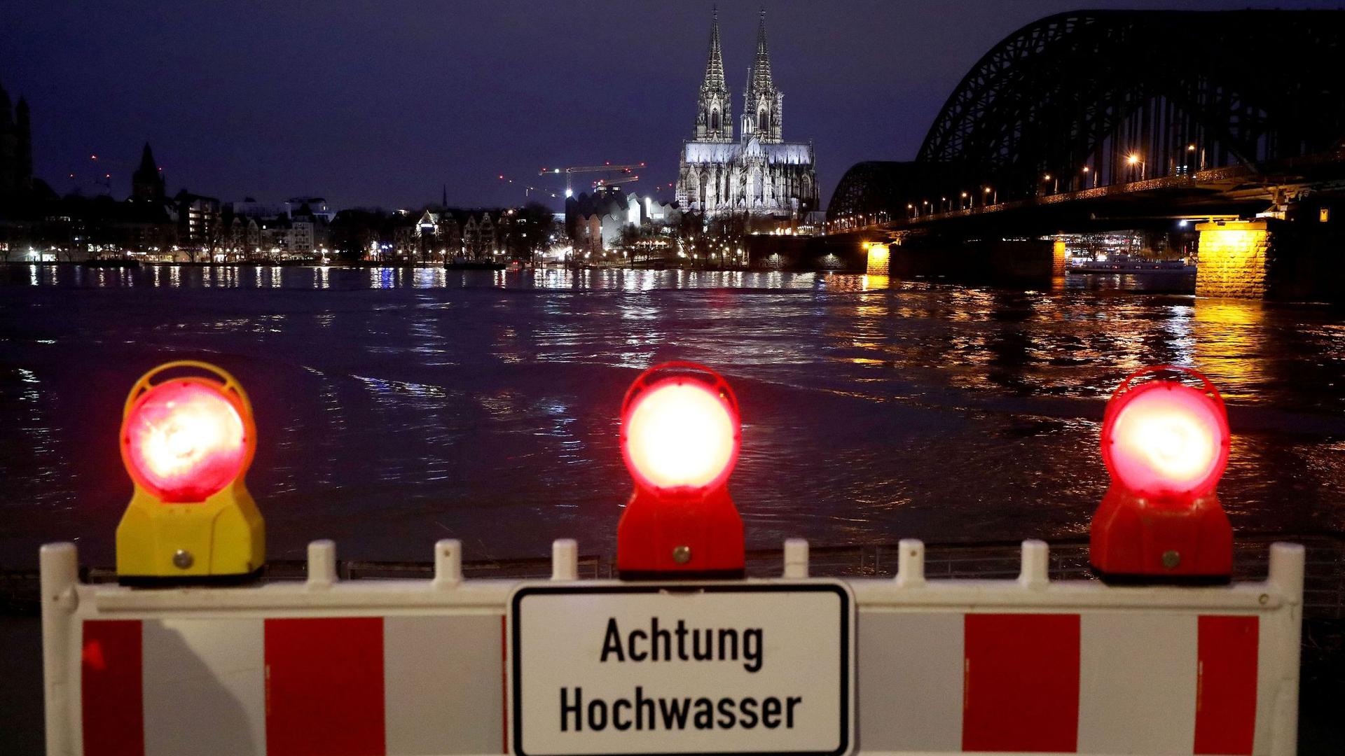 Eine Absperrung steht am Rheinufer. In Köln steigt der Pegelstand, für die Schifffahrt gibt es erste Einschränkungen.