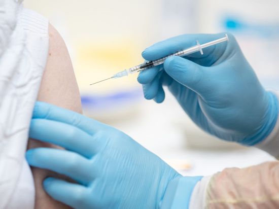 Eine Person wird in einem Impfzentrum von einem Notfallsanitäter mit dem Wirkstoff von Biontech/Pfizer gegen das Coronavirus geimpft.