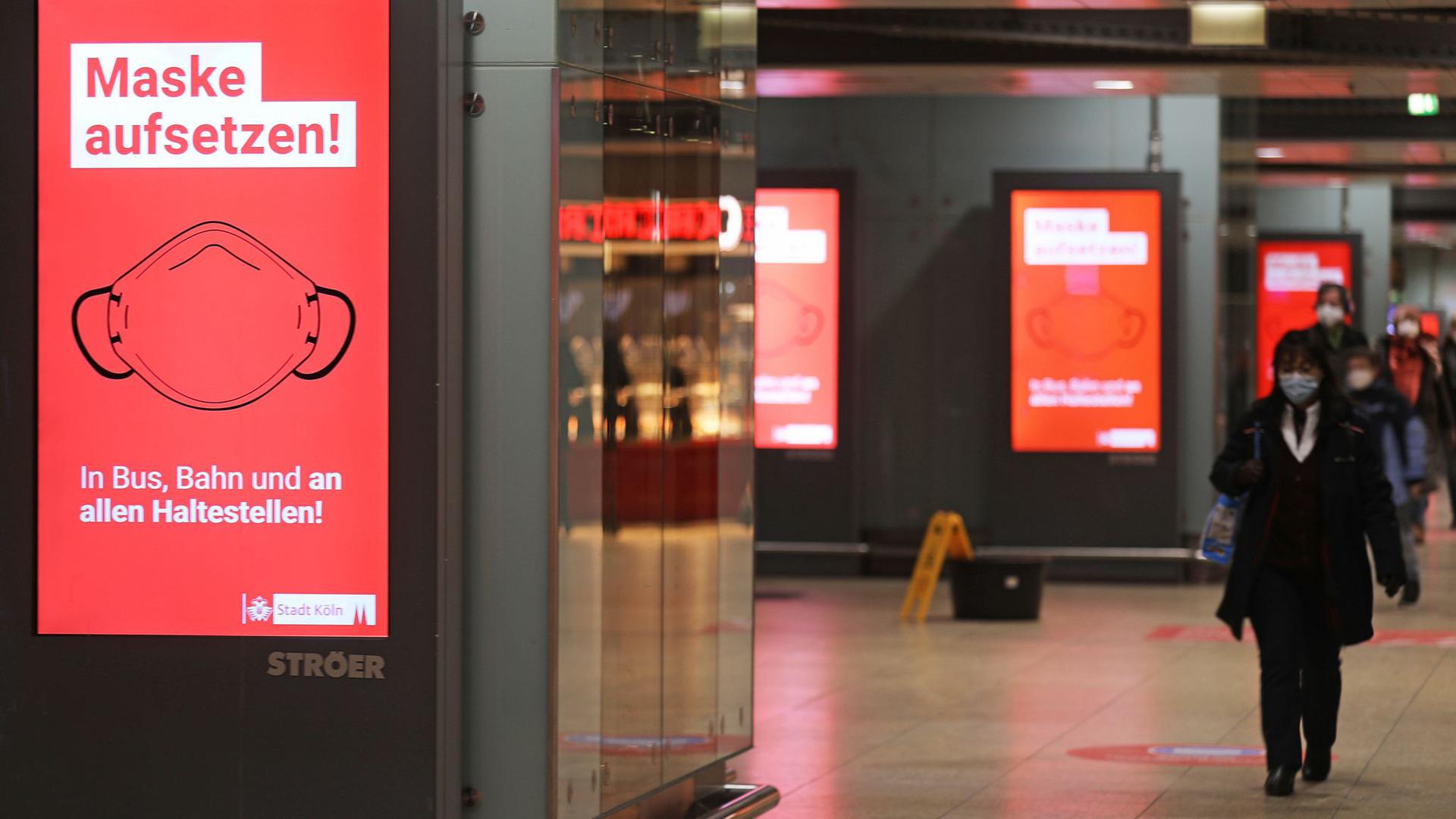 Der Schriftzug „Maske aufsetzten“ steht im Kölner Hauptbahnhof auf einem Display.