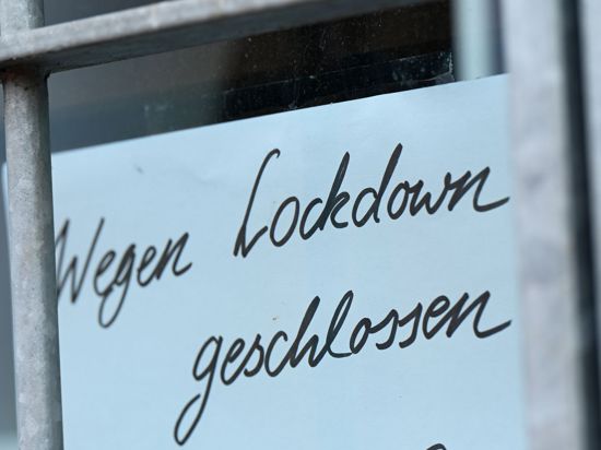 Ein Zettel mit der Aufschrift „Wegen Corona geschlossen“ hängt am Schaufenster eines Geschäfts.
