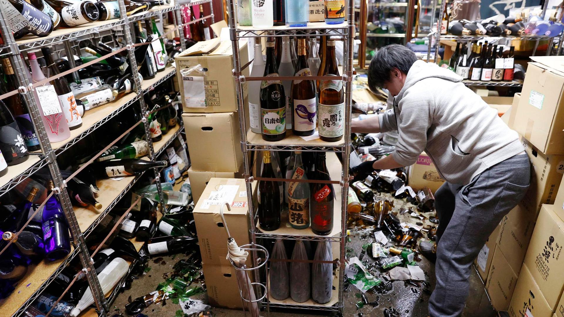 Der Inhaber eines Spirituosengeschäfts räumt nach einem starken Erdbeben in seinem Geschäft auf.