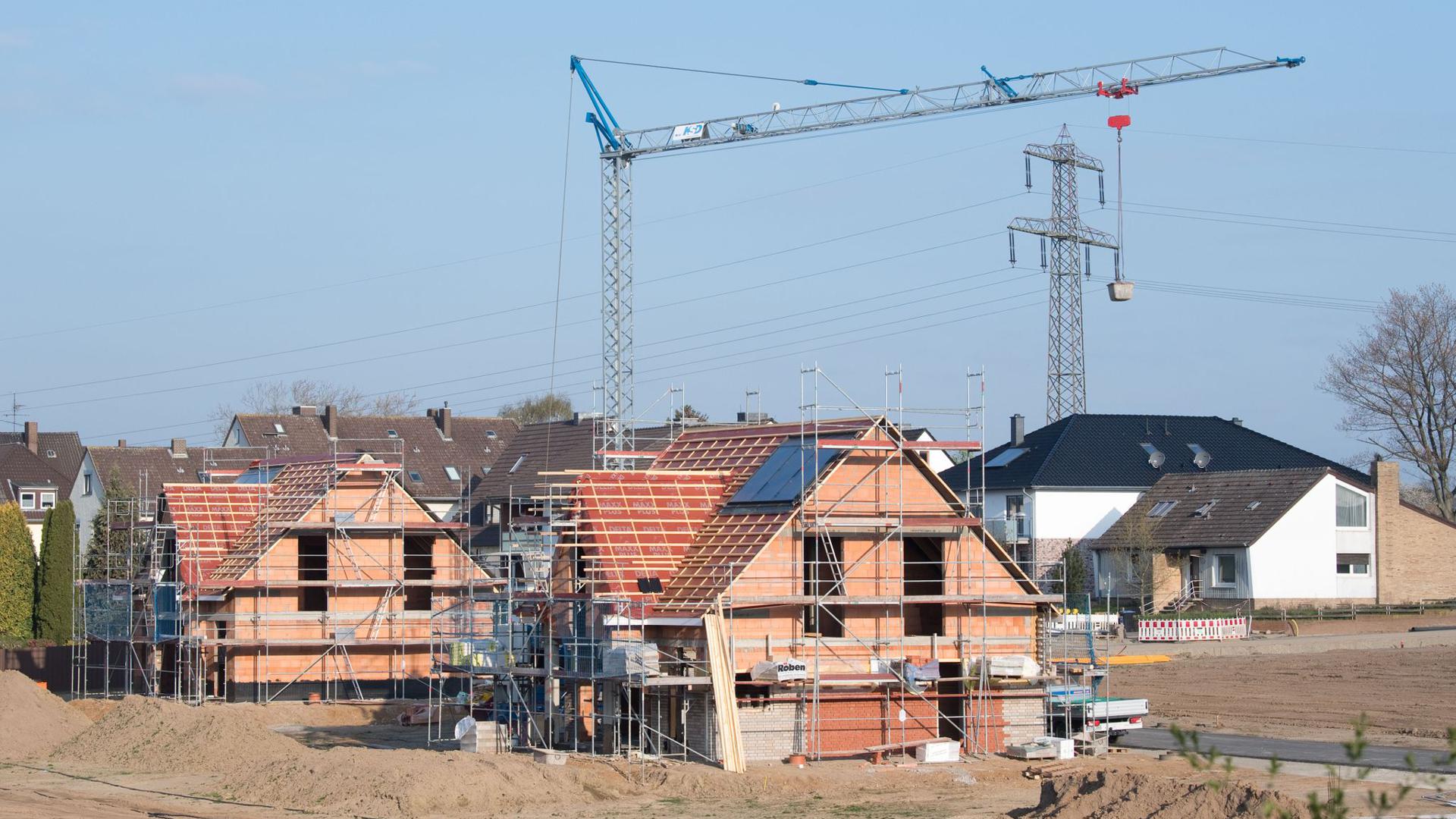 Einfamilienhäuser stehen im Rohbau in einem Neubaugebiet in der Region Hannover.