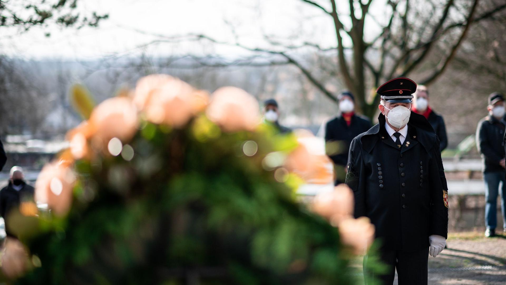 Ein Bergmann steht vor einem Kranz am Ehrenmal auf dem Friedhof in Bergkamen.