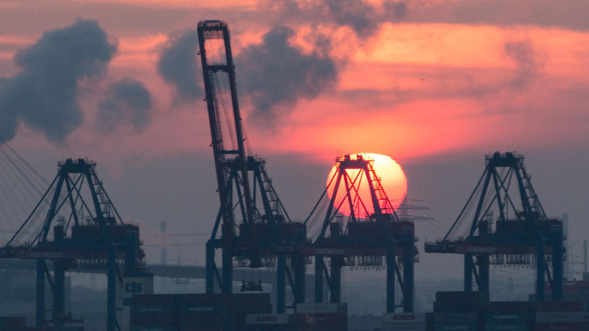 Sonnenuntergang hinter den Containerbrücken des HHLA Containerterminal Tollerort in Hamburg. Die Corona-Krise reißt tiefe Löcher in den Staatshaushalt.