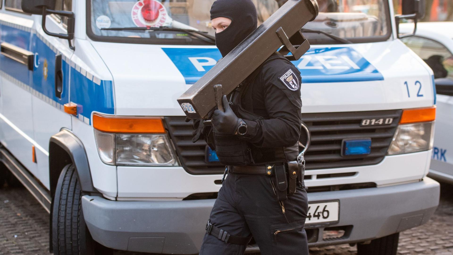 Ein Polizeibeamter trägt nach einer Razzia im Märkischen Viertel in Berlin eine Ramme.