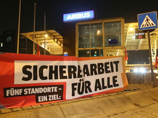 Ein Transparent mit der Aufschrift „Sichere Arbeit für Alle“ hängt vor den Werkstoren des Flugzeugherstellers Airbus in Hamburg-Finkenwerder.