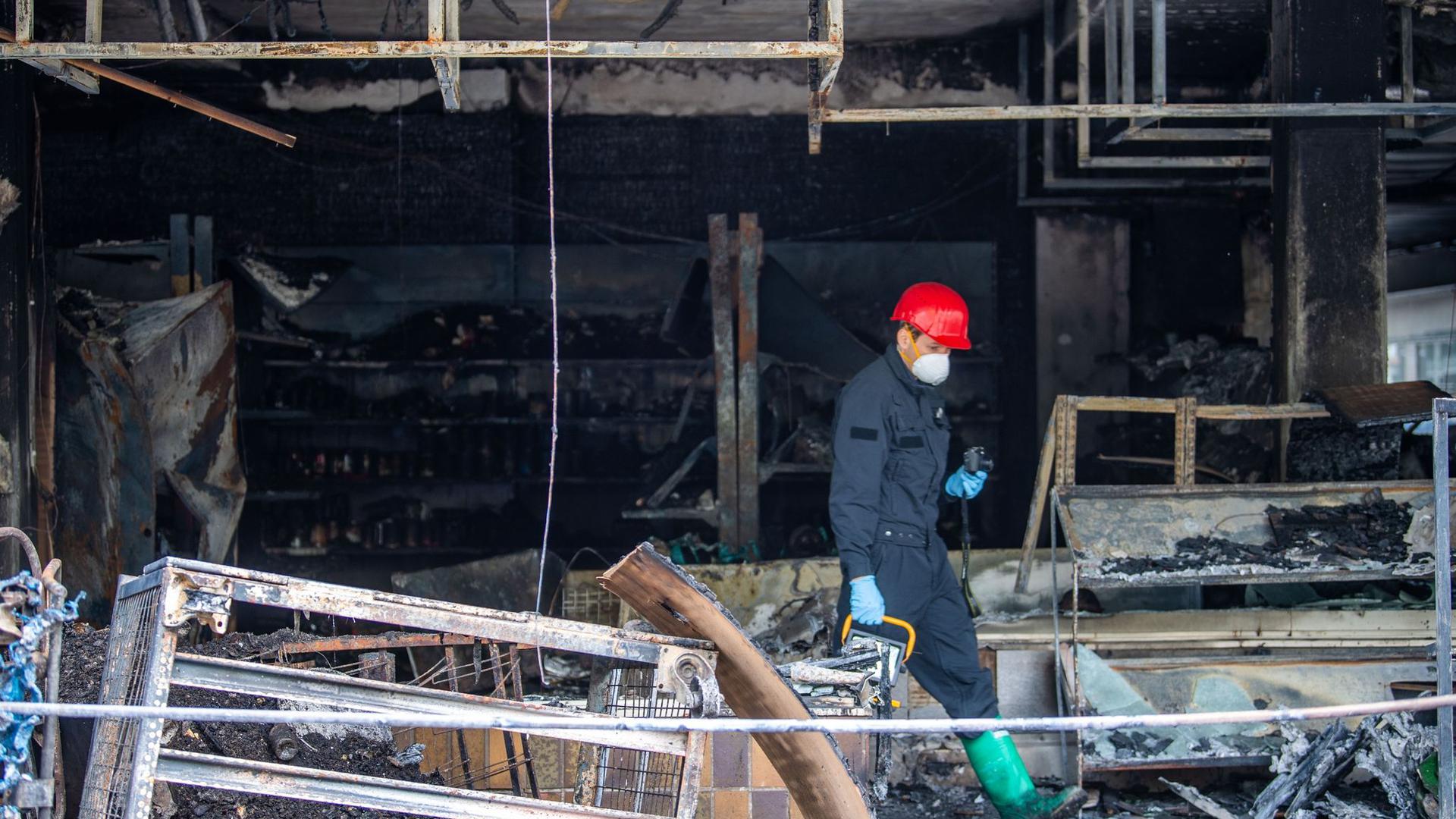 Ein Brandermittler der Polizei sucht drei Tage nach dem Brand eines türkischen Geschäfts nach Spuren.