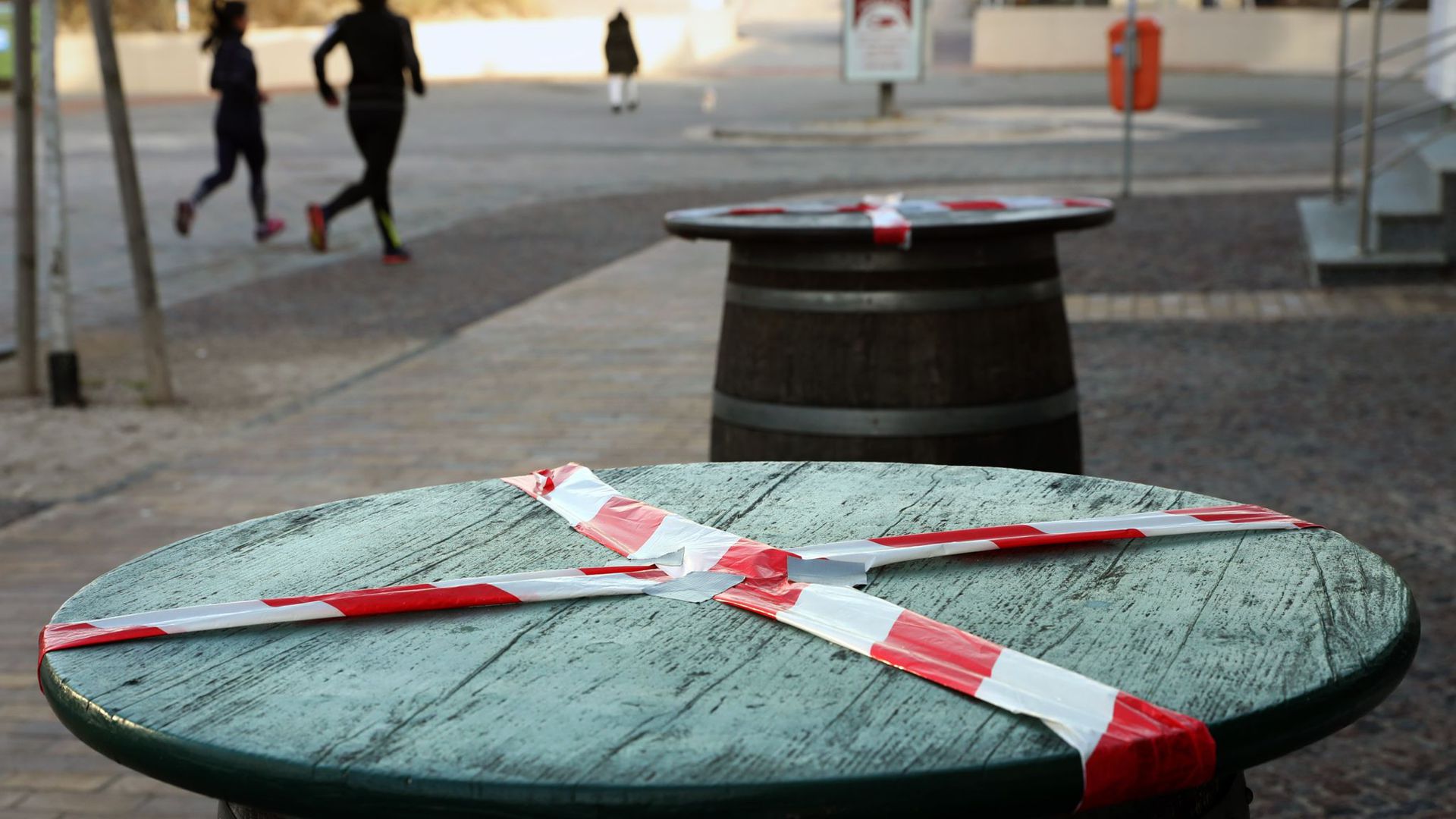 Kein gemütliches Beisammensein: Mit einem rot-weißen-Flatterband sind Stehtische an der Promenade des Ostseebades Warnemünde abgeklebt.