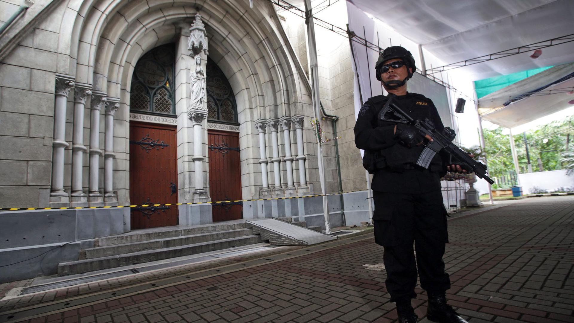 Ein bewaffneter indonesischer Anti-Terror-Polizist vor einer Kathedralkirche in Jakarta.