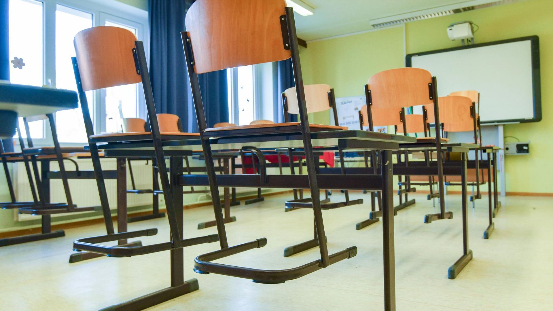 In einem leeren Unterrichtsraum an einer Schule sind die Stühle auf einen Tisch gestellt.