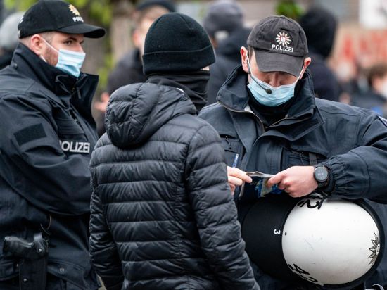 Polizisten kontrollieren die Personalien von einem Teilnehmer einer Demonstration in Hamburg.