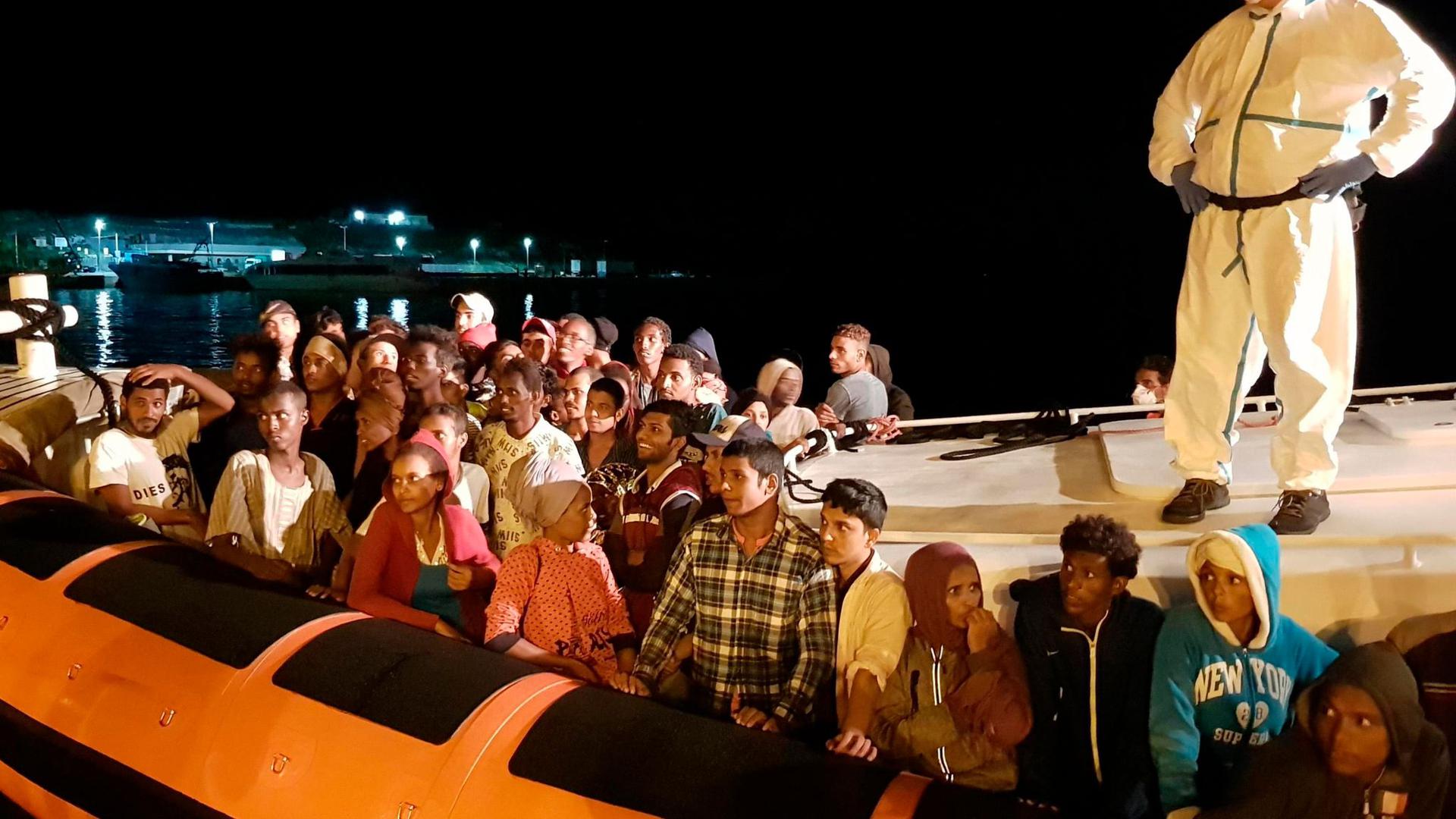 Flüchtlinge bereiten sich darauf vor, bei ihrer Ankunft im Hafen von Lampedusa aus einem Beiboot zu steigen (Archiv).