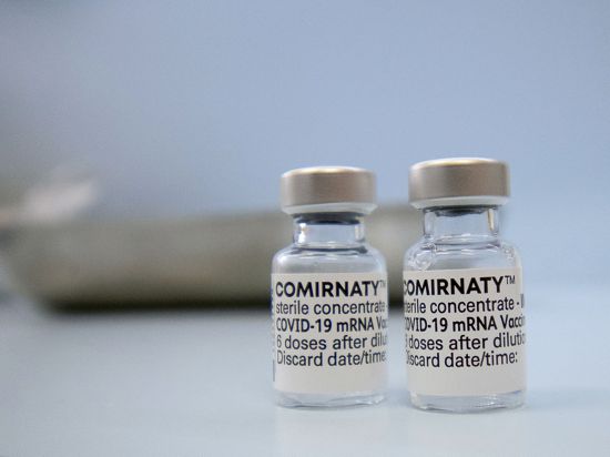 Fläschchen mit dem Biontech-Impfstoff Comirnaty stehen auf einer Theke in einer Hausarztpraxis.